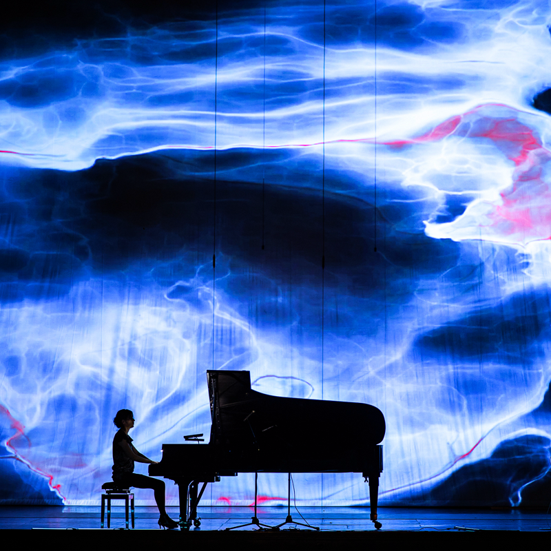 musicista che suona live il pianoforte con il video mapping immersivo di suoni estinzione